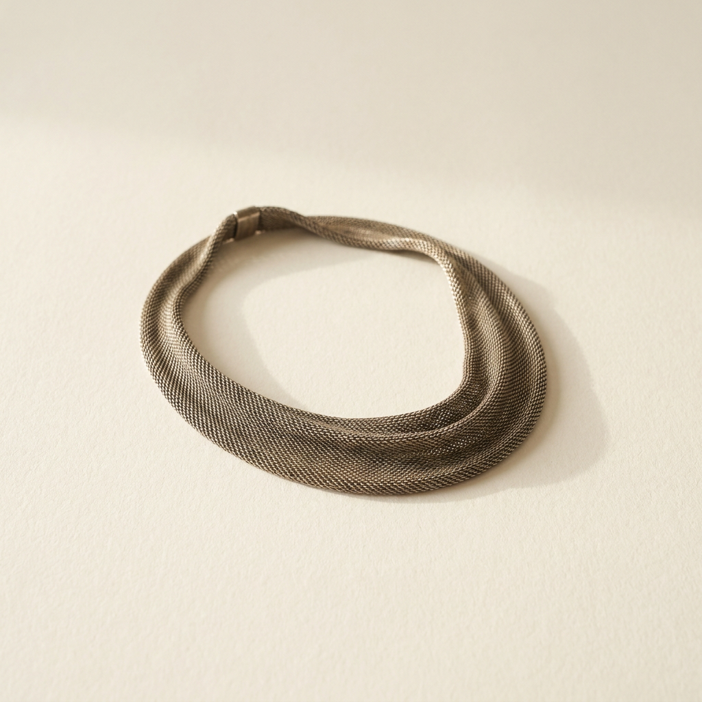 Woven sterling silver mesh collar necklace on paper